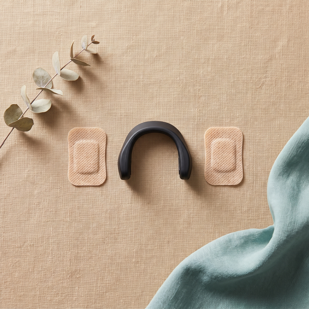 Flat lay of the Tezz AirGrip bridge and two adhesive pads on sand linen